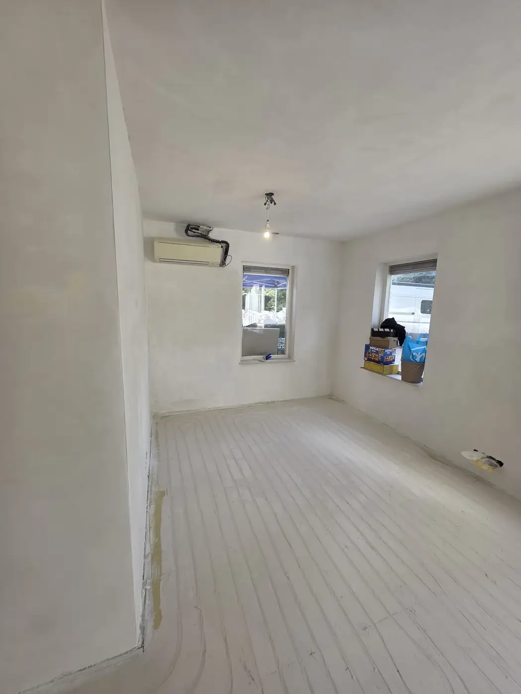 Kamer met airco en twee ramen volledig glad gestuukt, wanden en plafond