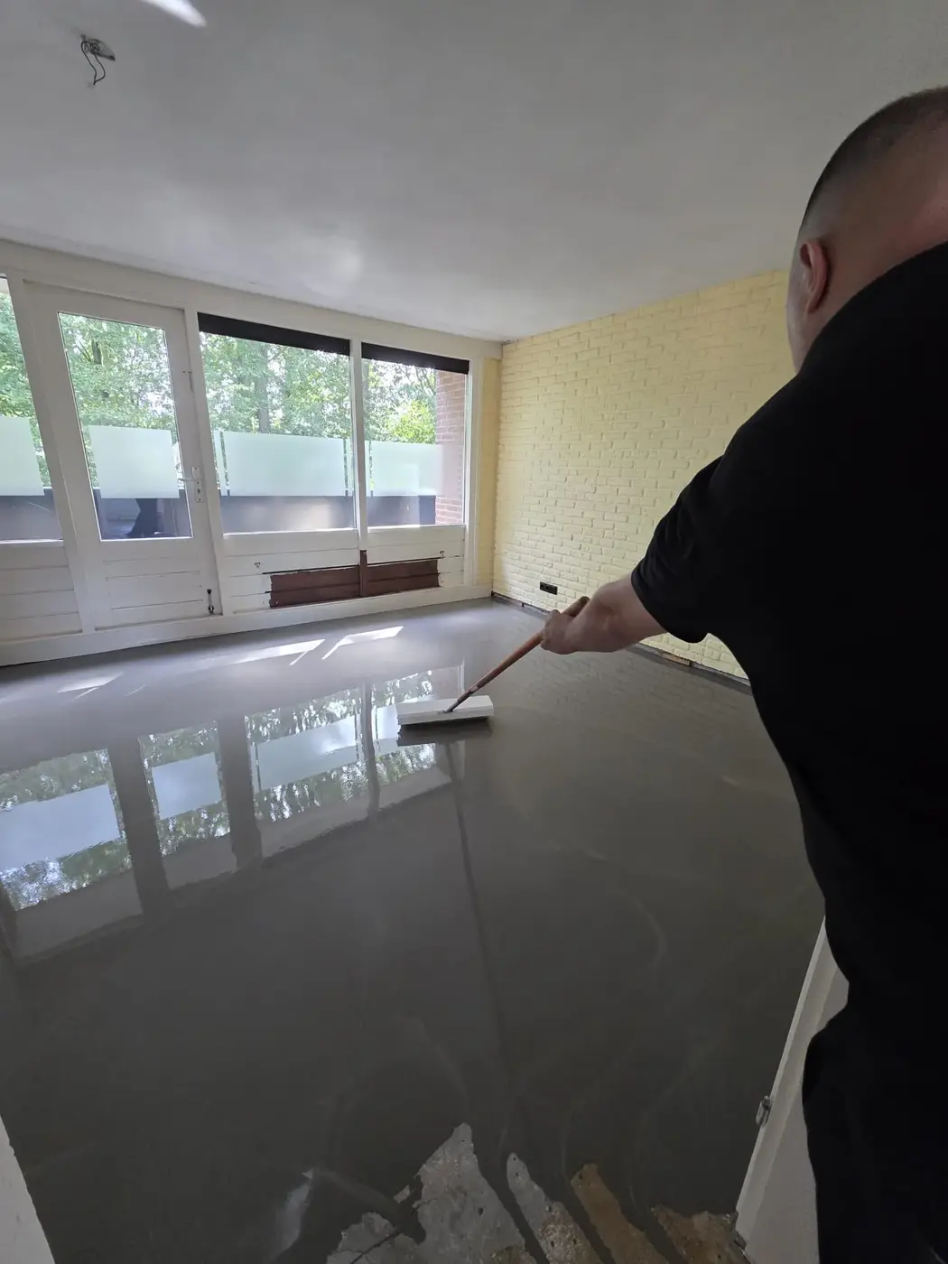 Egaliseren van de vloer met een spaan in een lichte woonkamer