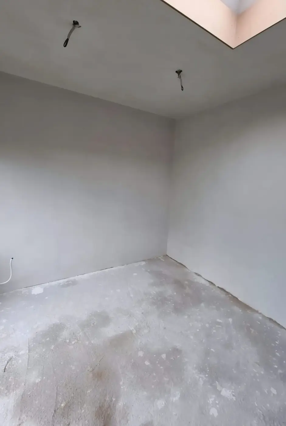 Slaapkamer onder een dakraam met glad gestuukte wanden en plafond
