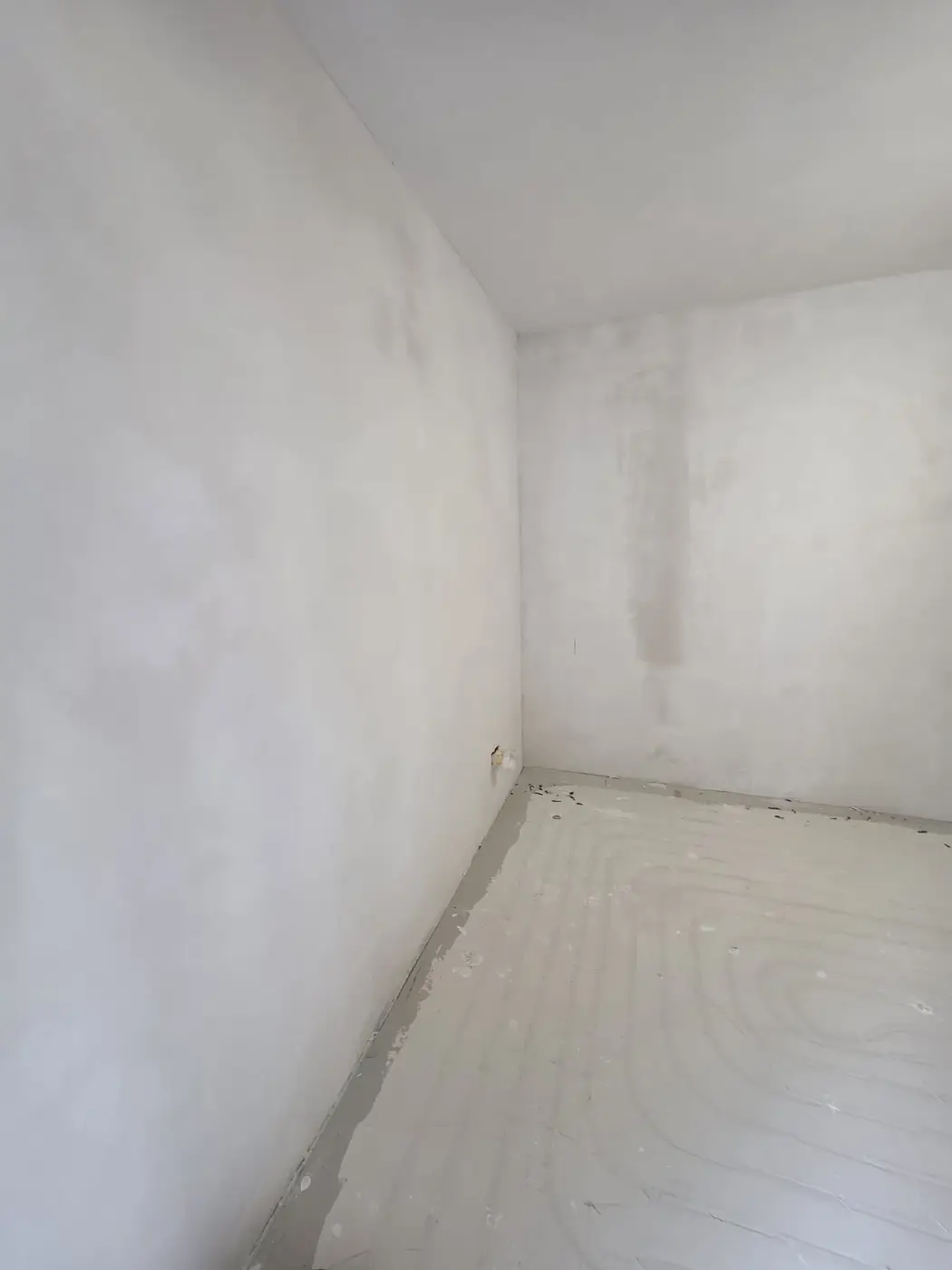 Hoek van een kamer strak gestuukt boven nieuwe vloerverwarming