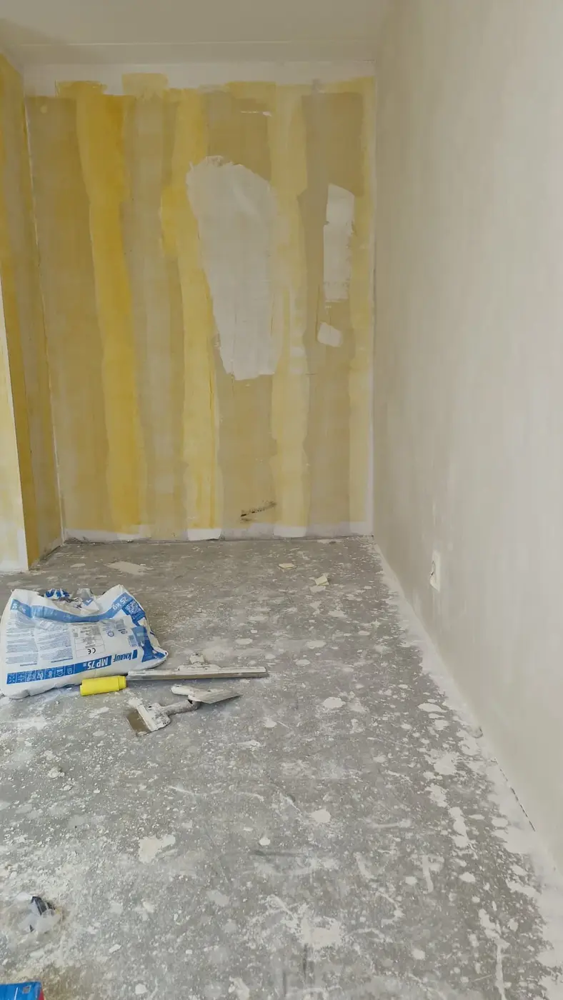 Wand met behangresten wordt voorbereid op nieuw stucwerk