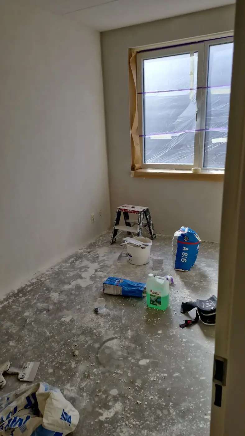 Kamer tijdens het stucwerk met afgeplakte kozijnen ter bescherming